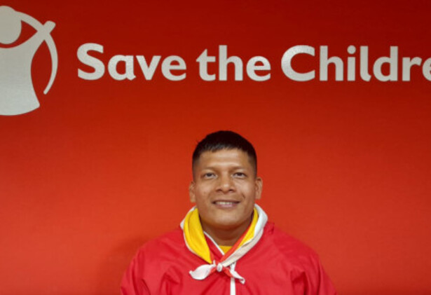 'Orange-red background with 'Save the Children' across it with man in foreground